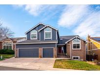 Two-story house with a brick and blue exterior, three-car garage, and landscaped lawn at 8293 S Ogden Cir, Littleton, CO 80122
