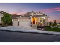 Charming home featuring a three-car garage, stone accents, and a beautifully landscaped front yard at 15604 Xenia Way, Brighton, CO 80602