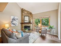 Comfortable living room with a stone fireplace, large window with natural light, and neutral-toned furniture at 1310 S Monaco Pkwy # 23, Denver, CO 80224