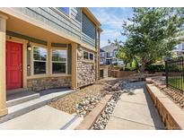 Charming home exterior featuring a red front door, stone accents, and manicured landscaping at 23560 Alamo Pl # B, Aurora, CO 80016