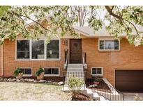 Charming red brick home featuring blooming trees and a well-maintained front yard at 5700 E Floyd Ave, Denver, CO 80222