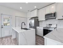 Modern kitchen featuring a waterfall island, stainless steel appliances, and white cabinets for a clean aesthetic at 12798 Ivy St, Thornton, CO 80602