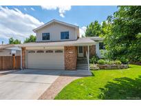 Charming two-story home featuring a brick facade, well-manicured lawn, and an attached two-car garage at 6134 W 83Rd Way, Arvada, CO 80003