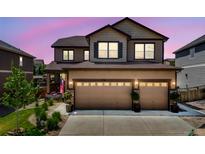 Charming two-story home featuring a three-car garage and landscaped front yard at dusk at 7514 Blue Water Dr, Castle Rock, CO 80108