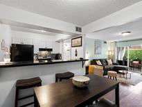 Cozy living room with an open floor plan connecting the kitchen and dining area and access to the outdoor patio at 7665 E Eastman Ave # 110, Denver, CO 80231