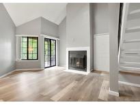 Bright living room features a fireplace, sliding glass door, modern flooring, and soaring vaulted ceilings at 832 S Vance St # F, Lakewood, CO 80226