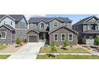 Charming two-story home featuring stone accents, a well-manicured lawn, and a welcoming facade at 671 Green Mountain Dr, Erie, CO 80516