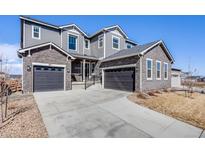 Charming two-story home with gray siding, stone accents, and a spacious three-car garage at 671 Green Mountain Dr, Erie, CO 80516