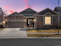 Charming single-Gathering home with stone accents, a two-car garage, and a well-maintained lawn at dusk at 23713 E Eads Dr, Aurora, CO 80016