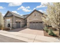 Stunning two-story home with a stone and stucco exterior, a three-car garage and a brick driveway at 5943 S Olive Cir, Centennial, CO 80111