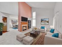 Bright living room featuring a fireplace, high ceilings, and comfortable seating arrangements at 18736 E Powers Pl, Aurora, CO 80015