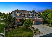 Beautiful two-story home with a well-manicured lawn and mature trees at dusk at 16267 W 59Th Pl, Golden, CO 80403
