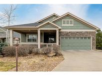 Charming home featuring a stone facade, two-car garage, inviting front porch, and nicely landscaped front yard at 8853 E 151St Ct, Thornton, CO 80602