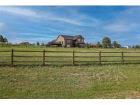 Two-story home featuring a deck, visible through a wooden fence, surrounded by a lush green lawn at 2501 Remington Rd, Elizabeth, CO 80107