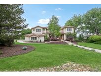 Expansive front lawn with a charming two-story home featuring a tile roof and mature trees at 7760 Crestview Ln, Niwot, CO 80504