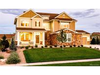 Charming two-story home with a covered front porch, manicured lawn, stone accents, and an attached garage at 23270 E Rockinghorse Pkwy, Aurora, CO 80016