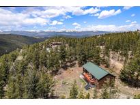 Charming cabin with red deck nestled among lush trees, showcasing stunning mountain views at 72 Rudi W Ln, Golden, CO 80403