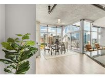 Modern dining area with city views through floor-to-ceiling windows and stylish furnishings at 1700 Bassett St # 1111, Denver, CO 80202