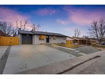 Ranch style home with a newly paved driveway and modern gray garage door at 1061 Elbert St, Denver, CO 80221