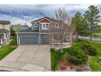 Inviting two-story home featuring a well-manicured lawn, gray siding, a spacious porch, and an attached two-car garage at 16453 Homestead Ct, Parker, CO 80134