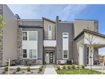 Modern townhome with a landscaped front yard and a gray and white facade with outdoor seating at 2475 W 69Th Pl, Denver, CO 80221