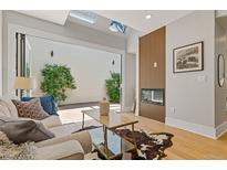 Bright living room featuring skylights, a fireplace, modern decor, and seamless indoor-outdoor flow to the patio at 434 Clayton St, Denver, CO 80206