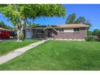 Charming brick home with a lush green lawn and mature trees, perfect for curb appeal at 8250 Chase Way, Arvada, CO 80003