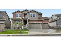 Two-story home with mixed siding, stone accents, three-car garage, and a well-maintained front yard at 4592 Windmill Dr, Brighton, CO 80601