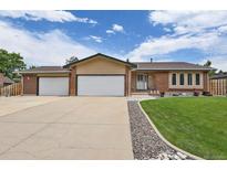 Charming single-story home with a brick facade, a well-manicured lawn, and an attached two-car garage at 7784 Lewis St, Arvada, CO 80005