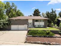 Charming brick home with a three-car garage, mature trees, and a well-maintained front yard at 2502 S Lima St, Aurora, CO 80014