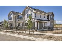 Charming townhome featuring stone accents, fenced yard, and modern architectural details at 95 N Vandriver Pl, Aurora, CO 80018