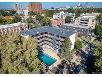 Apartment building featuring a swimming pool and an exterior staircase with city views and mature shade trees at 33 N Corona St # 205, Denver, CO 80218