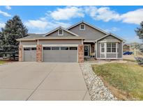 Charming gray two-story home featuring a three-car garage, brick accents, and well-kept landscaping at 2347 Switch Grass Way, Castle Rock, CO 80109