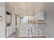 Cozy kitchen with white cabinetry, a breakfast bar with stone accent wall, and modern appliances at 7683 S Steele St, Centennial, CO 80122