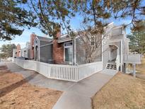 Gray townhouse exterior with brick accents, white picket fence, and patio at 9051 Bear Mountain Dr, Highlands Ranch, CO 80126