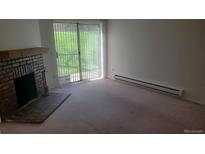 Spacious living room featuring a cozy brick fireplace and sliding glass doors to the outside at 14806 E 2Nd Ave Ave # 105G, Aurora, CO 80011