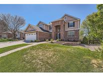 Inviting brick and tan two-story home featuring a well-maintained lawn and attached two car garage at 3549 Mallard Dr, Highlands Ranch, CO 80126