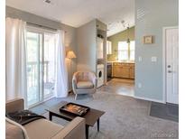Cozy living room with a sliding glass door to the balcony, and a stacked washer and dryer at 9640 W Chatfield Ave # A, Littleton, CO 80128