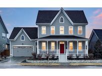 Inviting two-story home showcasing a red front door and a covered front porch with white railings at 5228 N Xenia St, Denver, CO 80238