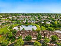 Stunning aerial view of townhomes surrounding a tranquil pond, with lush greenery and a clear blue sky at 3240 W 114Th Cir # D, Westminster, CO 80031