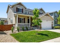 Charming two-story home with a well-manicured lawn, inviting front porch, and attached two-car garage at 16975 Melody Dr, Broomfield, CO 80023