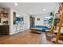 Bright living room featuring hardwood floors, natural light, and an open layout, adjacent to the kitchen at 2870 Pontiac St, Denver, CO 80207