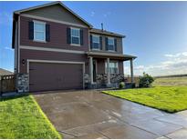 Two-story home with a well-manicured lawn, brown siding, stone accents, and a two-car garage at 975 Alta St, Lochbuie, CO 80603