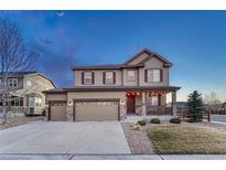 Charming two-story home featuring a three-car garage and inviting front porch with stone accents and a well-maintained lawn at 7310 Blue Water Dr, Castle Rock, CO 80108