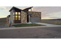 Modern home featuring stone accents, a gray garage door, and professionally landscaped front yard at 5741 Doc Bar Circle, Larkspur, CO 80118