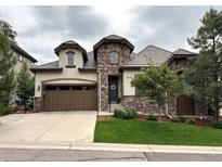 Charming two-story home featuring a stone facade, manicured lawn, and a two-car garage in a Gathering-friendly neighborhood at 6875 Northstar Ct, Castle Rock, CO 80108