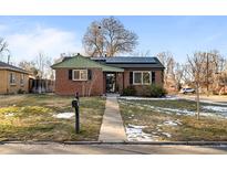 Brick ranch home with green accents, solar panels, and a landscaped yard at 1585 Roslyn St, Denver, CO 80220