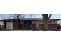 Charming single-story home featuring a brick and stone facade, a lamp post, and an attached garage at 426 Kenton St, Aurora, CO 80010