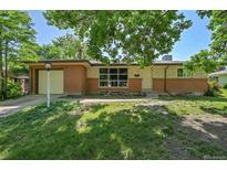 Charming brick home with large front windows and attached garage, shadowed by a large tree at 426 Kenton St, Aurora, CO 80010