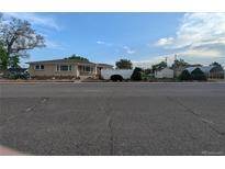 Street view of home with detached carport and fenced yard with mature trees at 1009 Bush St, Brighton, CO 80601